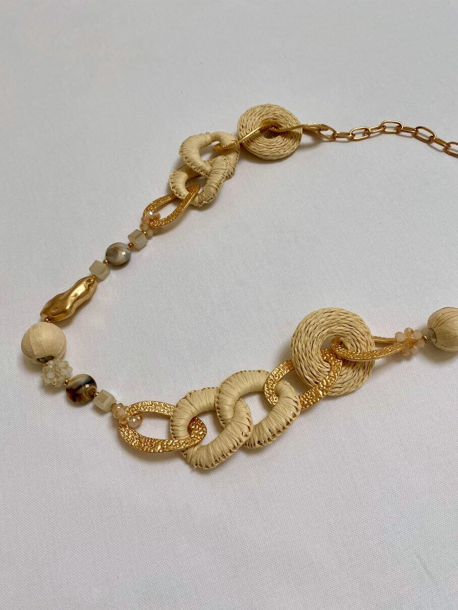 Lange goldene Halskette mit beigefarbenen Anhängern