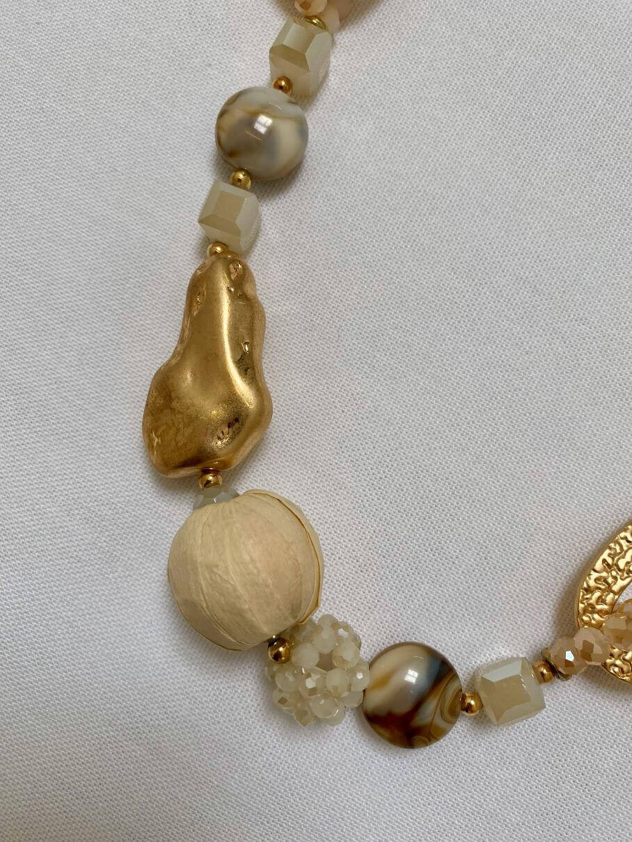 Lange goldene Halskette mit beigefarbenen Anhängern